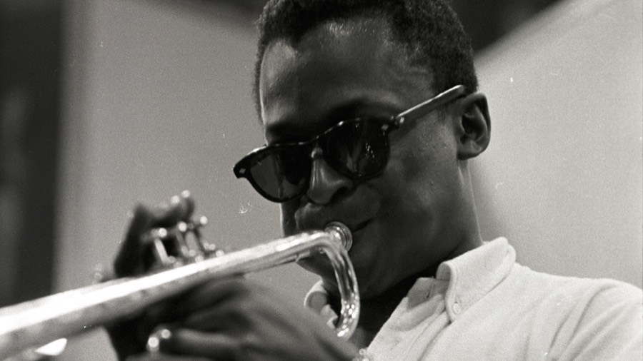 Miles Davis in sunglasses playing the trumpet